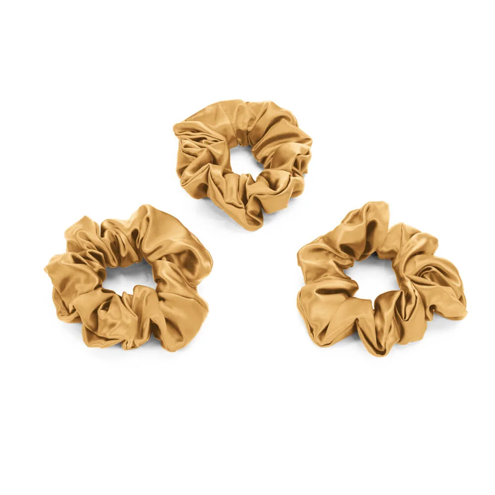 Three Gold Blissy silk scrunchies arranged on a white studio background.